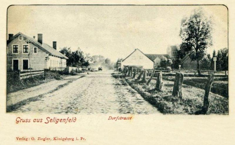 Postkarte - Gruß aus Seligenfeld, Dorfstraße, im Hintergrund rechts die Evangelische Pfarrkirche, das Wohngebäude im Vordergrund links steht heute noch und ist auf einem der folgenden Aufnahmen zu erkennen.